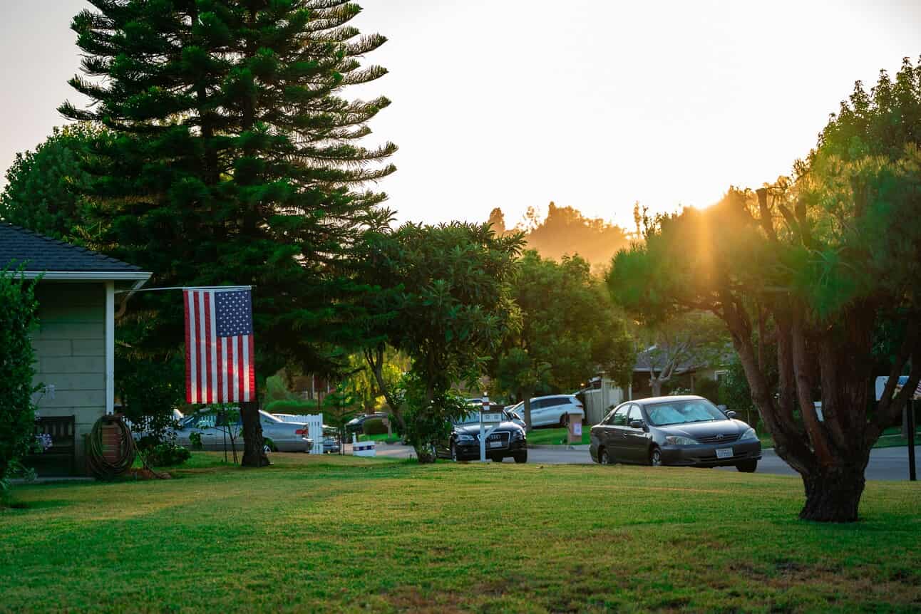 Cars parked outside of a house with a nice lawn.