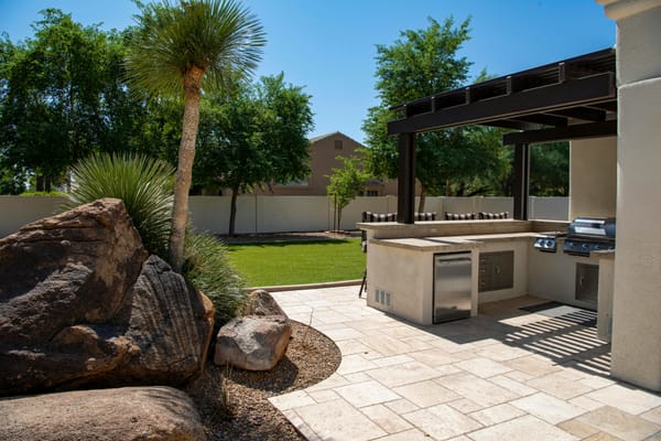 Outdoor kitchen with pergola and stone flooring.