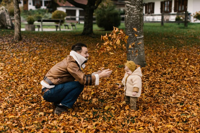 Family playing in leaves in their yard.